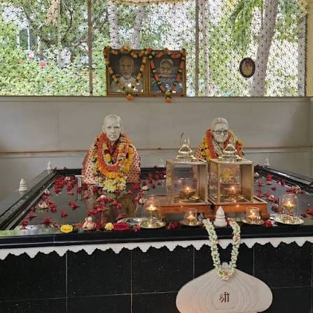 The Divine Parents Samadhi — garlanded busts of Easwaramma and Peddavenkama Raju amid flowers and lamps