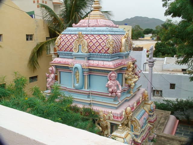 The pastel-painted shrine tower of the Sivalayam temple at Bhagawan's birthplace, the Puttaparthi hills behind